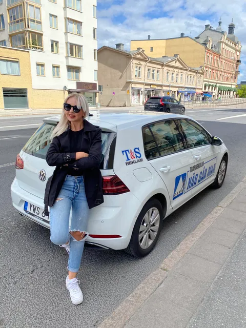 Körkortstagare poserar vid övningsbilen på stadsgata i Örebro