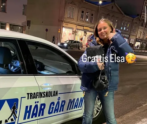 Glad elev firar körkortet bredvid övningsbilen