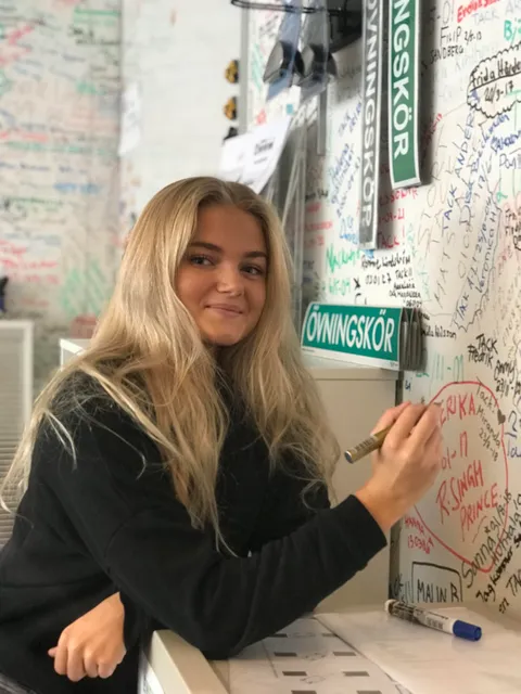 Elev skriver sitt namn på namnväggen bland övningskörsskyltar