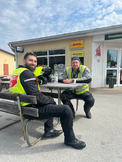Två MC-förare tar en paus vid ett bord utomhus