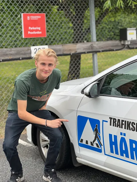 Ung man pekar stolt på övningsbilen efter godkänt förarprov