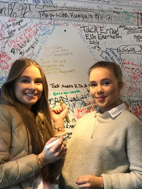 Två elever skriver sina namn på trafikskolans namnvägg